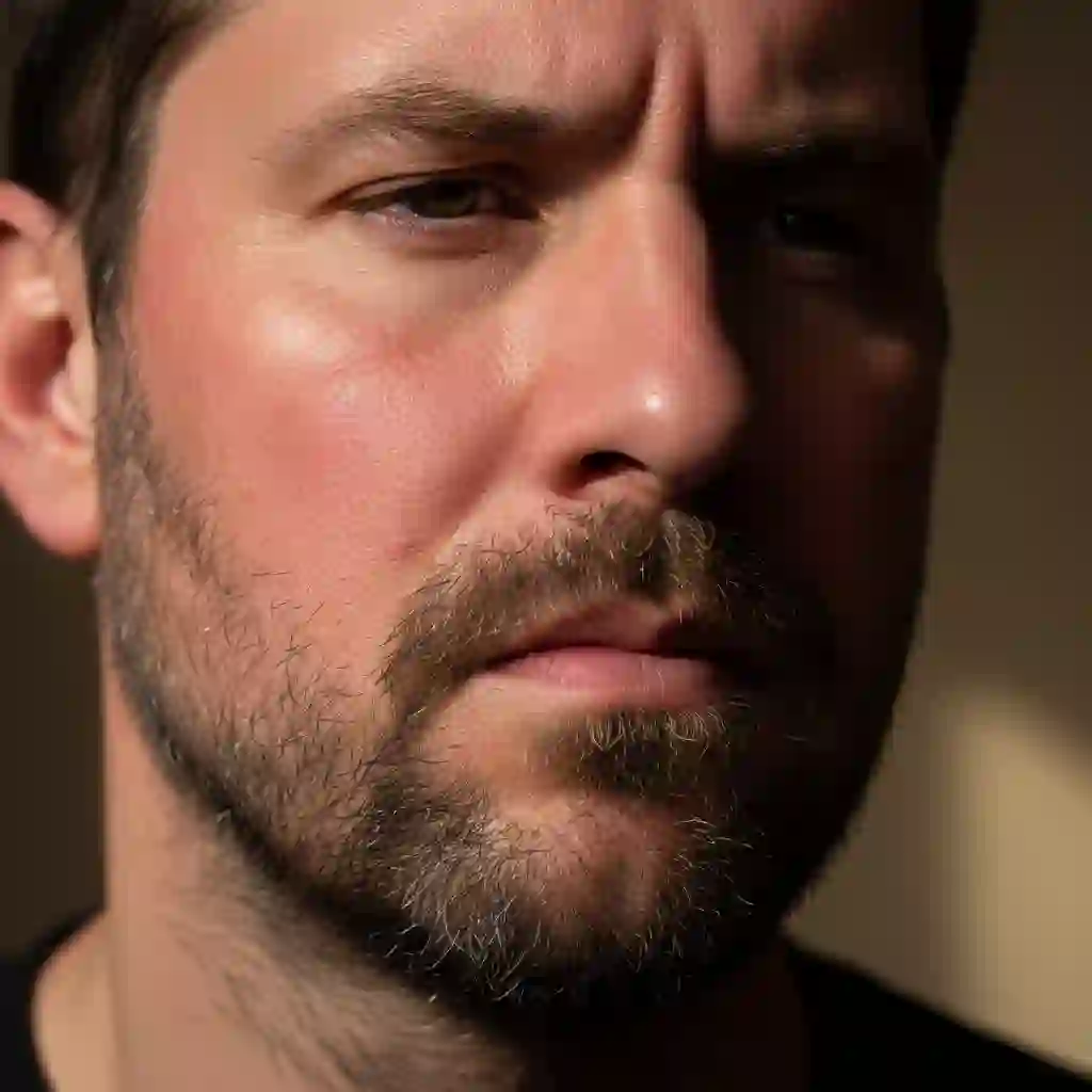 A man examines his five o’clock shadow in the mirror, illustrating the everyday struggle before starting beard laser hair removal to reduce stubble, razor burn, and achieve smoother, longer-lasting clean-shaven results.