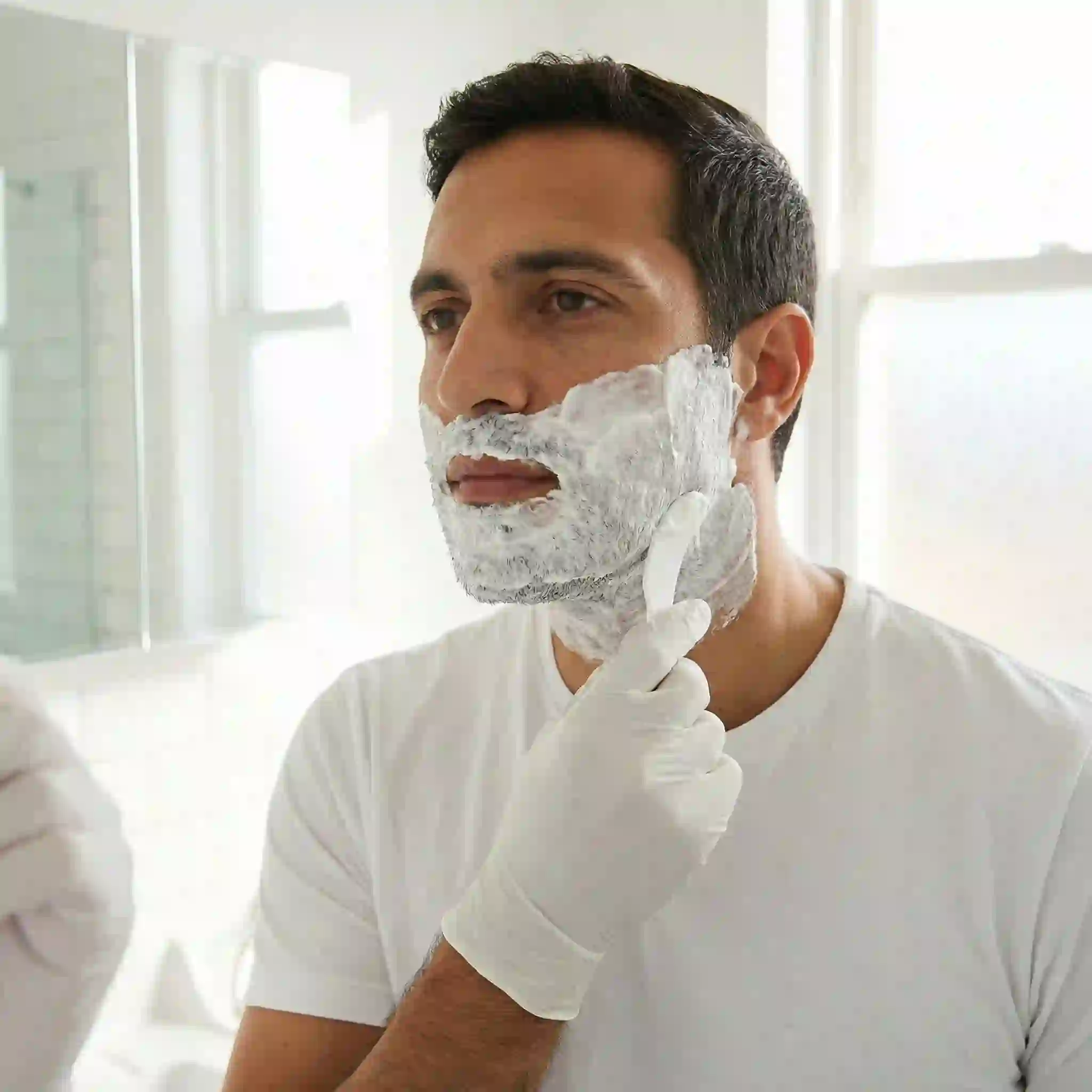 Close-up of a thick layer of beard removal cream being applied to the jawline, demonstrating the correct application technique to fully cover the hair and ensure a uniform, effective removal without missing any patches.