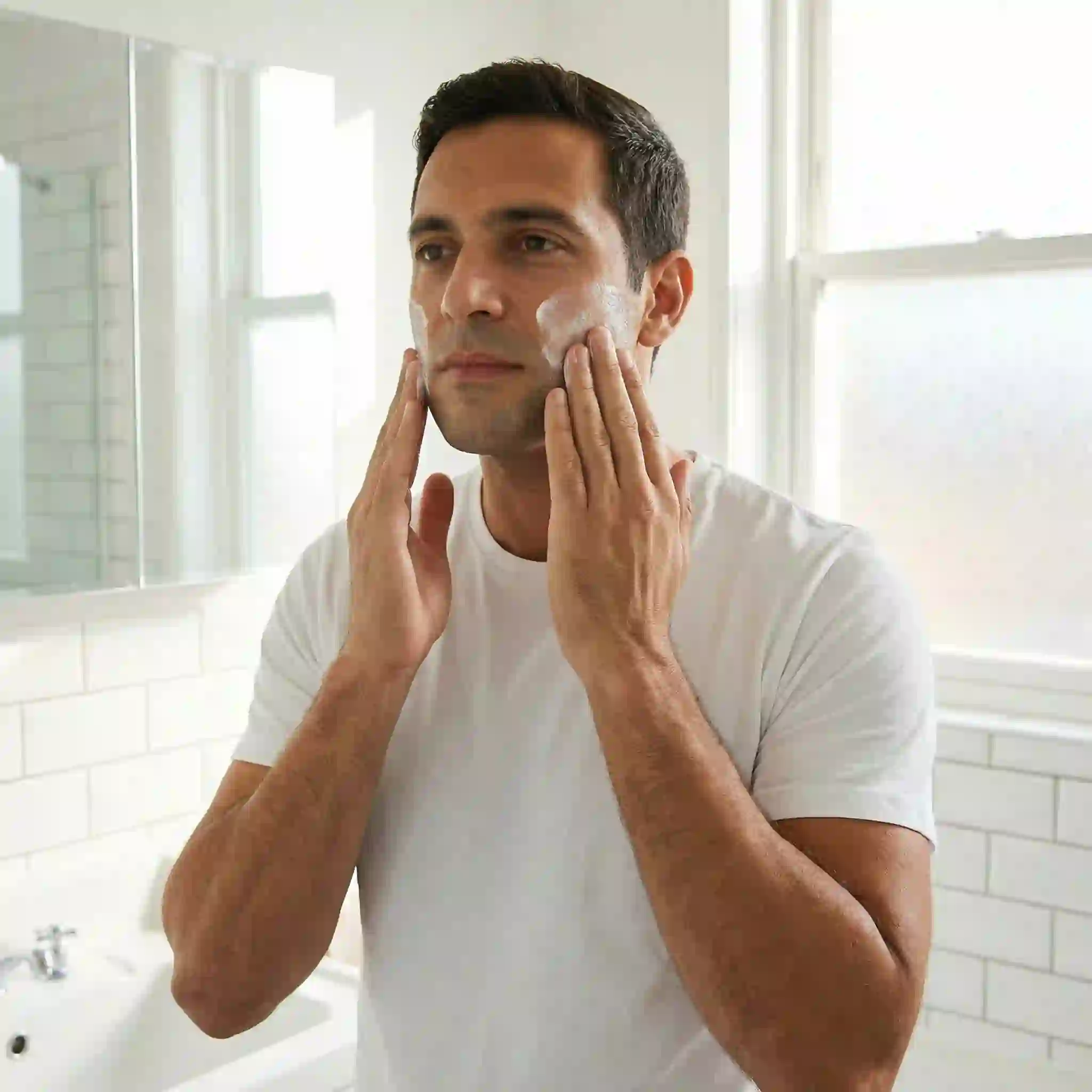 Man applying a soothing moisturizer to his clean-shaven face after using beard removal cream, highlighting the essential aftercare step to replenish moisture, calm the skin, and maintain a healthy barrier for a long-lasting result.