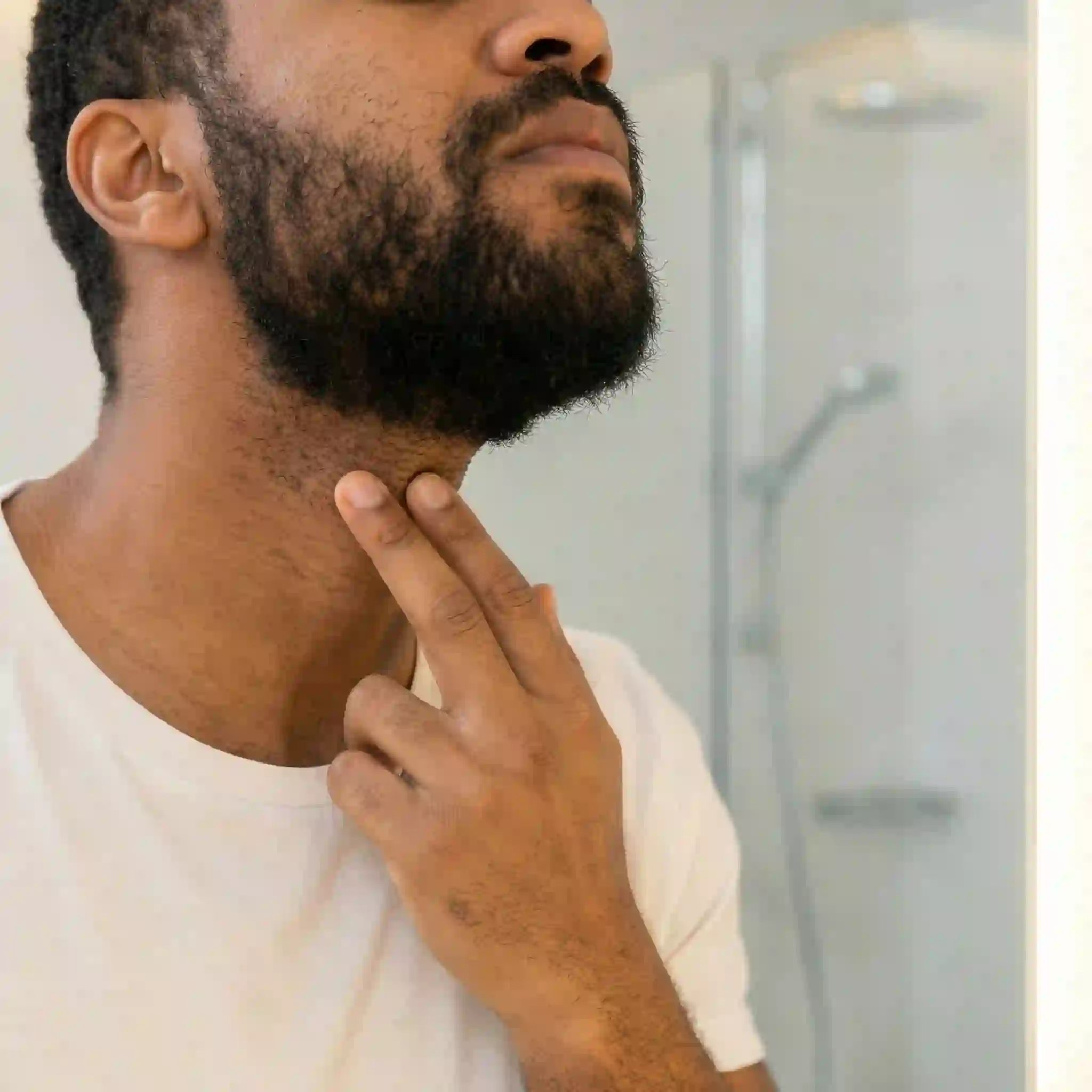 Positioning the curved edge of a flexible beard liner tool two fingers above your Adam's apple creates a natural looking curve from ear to ear, defining your neckline perfectly before you start to shave.