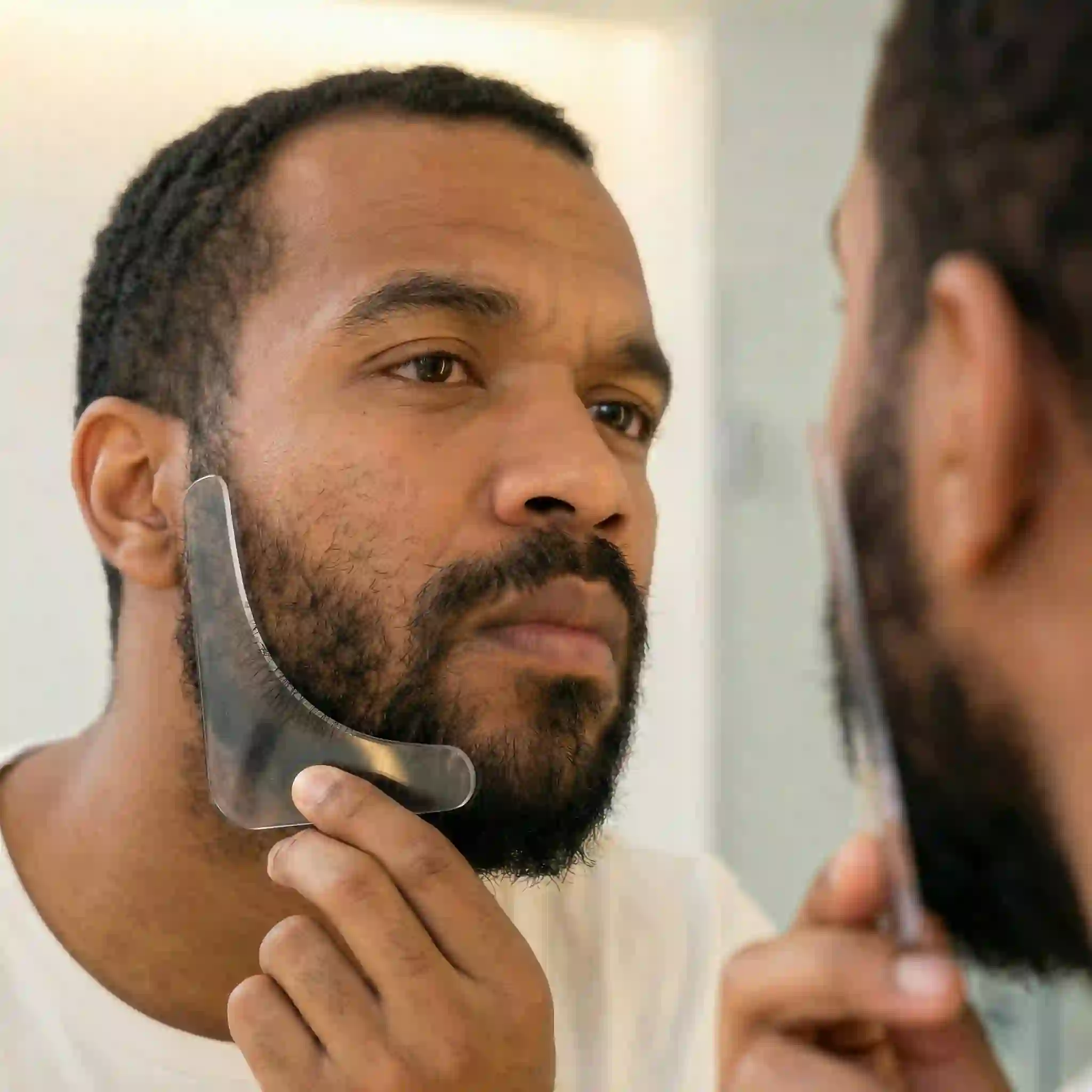 Placing a transparent facial hair styling guide or beard liner tool against your cheek allows you to see the hair underneath while establishing a sharp line from your sideburn down to your mustache.