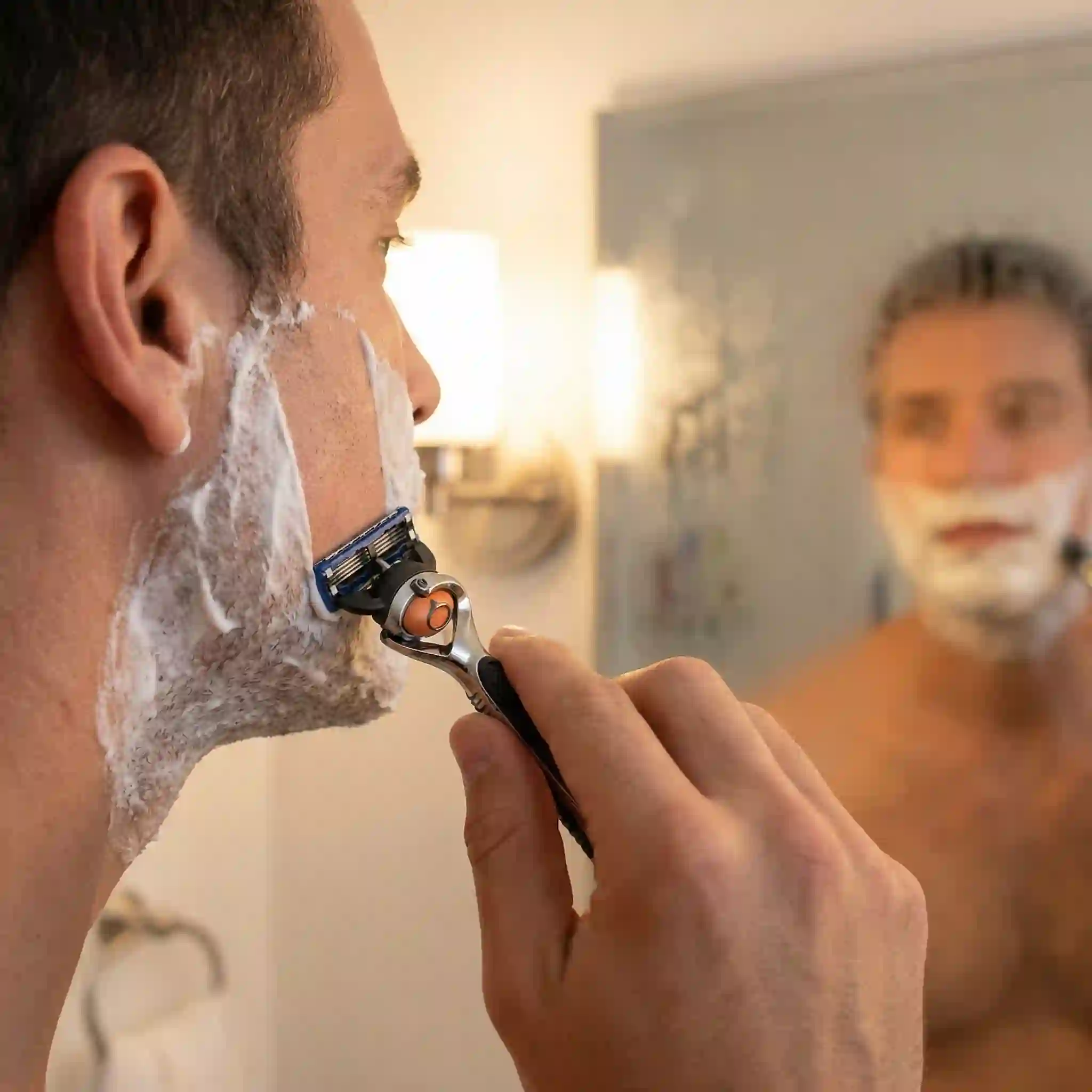 Shaving with the grain for a clean shaven result, using light short strokes to remove facial hair while protecting sensitive skin.
